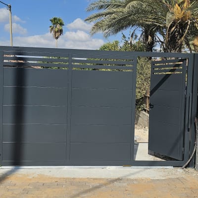 שער מתכת אפור עם דלת פתוחה בחצר
