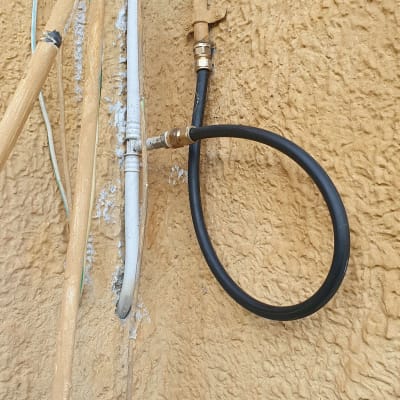 צינור שחור מחובר לברז על קיר חיצוני