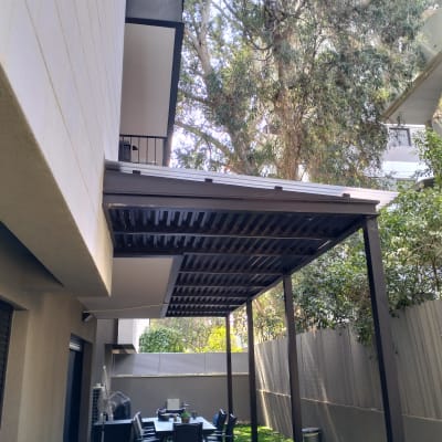 פרגולה מעץ בגינה עם שולחן וכיסאות