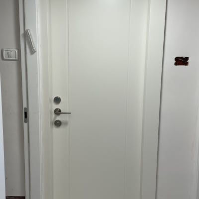 דלת לבנה עם ידית מתכת וכפתורי נעילה