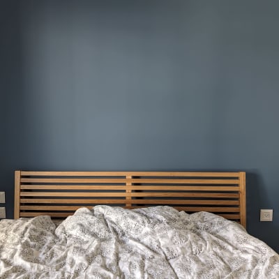 קיר צבוע בכחול כהה מאחורי מיטה