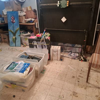 קופסאות אחסון שקופות וחפצים ממוינים בחדר עמוס בתהליך סידור וארגון