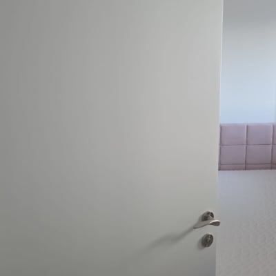 דלת לבנה עם ידית מתכת בחדר שינה