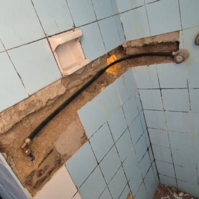 צינור חשוף בקיר עם אריחים שבורים