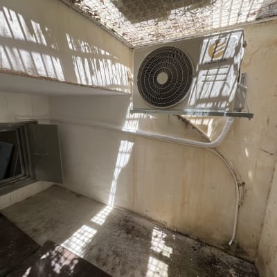 יחידת מיזוג אוויר מותקנת על קיר חיצוני עם צינורות מחוברים