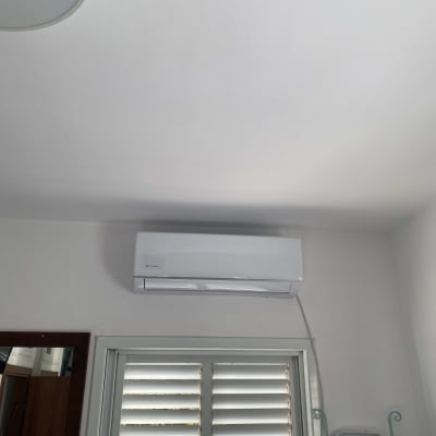 מזגן מותקן על קיר מעל חלון עם תריסים