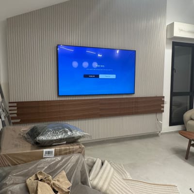 טלוויזיה מותקנת על קיר עם חיפוי עץ, חפצים מכוסים בניילון