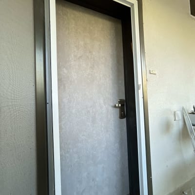 דלת מצופה עם ידית מתכת על קיר בהיר