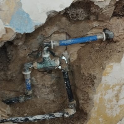 צנרת מים חשופה בקיר עם תיקונים
