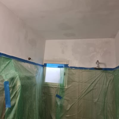 חדר עם קירות צבועים ויריעות פלסטיק להגנה.