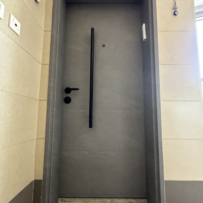 דלת אפורה עם ידית שחורה בקיר בהיר
