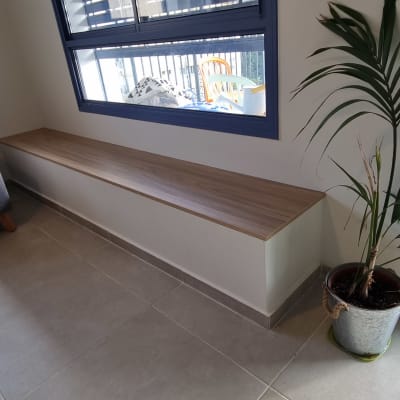 ספסל עץ מתחת לחלון עם תריסים