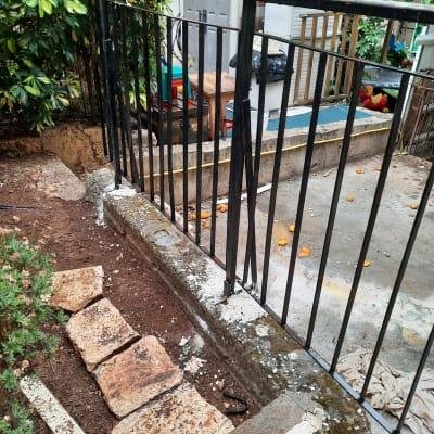 מעקה מתכת שחור עם עמודים אנכיים בגינה