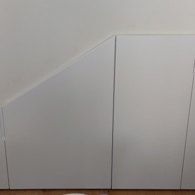 ארון לבן מתחת למדרגות עם דלתות משופעות