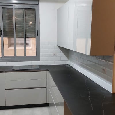 מטבח משופץ עם ארונות לבנים ומשטח עבודה כהה