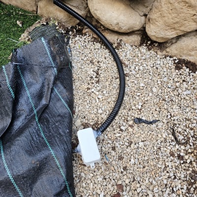 צינור חשמל שחור מחובר לקופסת חיבורים על קיר אבן