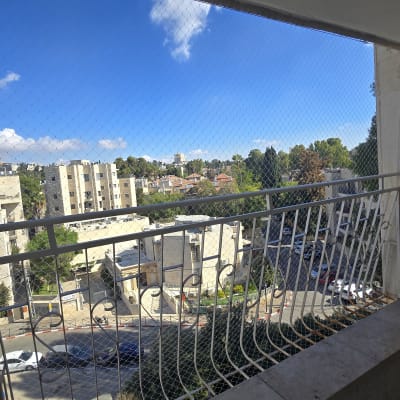 התקנת רשת שקופה נגד יונים המכסה את פתח המרפסת בבניין מגורים