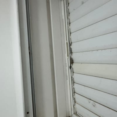 חלון עם תריסים לבנים ומסגרת מתכתית