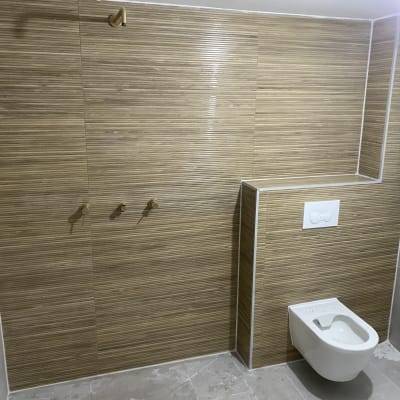 שירותים מותקנים על קיר עם אריחים חומים