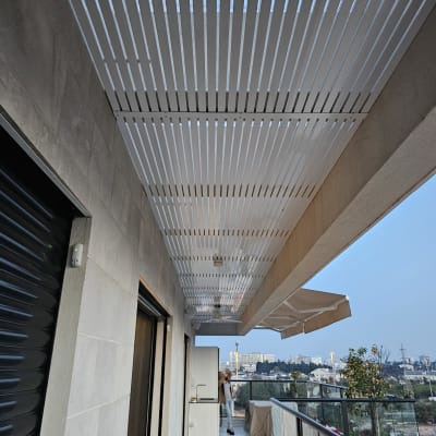 פרגולה מאלומיניום עם קורות לבנות במרפסת