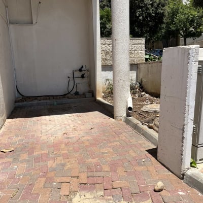 שטח מרוצף עם עמודים וקיר, ללא פעילות גיזום נראית לעין