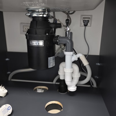 כיור עם צנרת וכלים מתחת לכיור במטבח