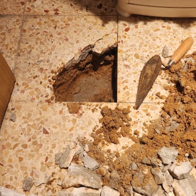 חפירה ברצפה עם כלי עבודה ואבנים שבורות