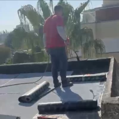 אדם עובד על איטום גג עם יריעות ביטומניות