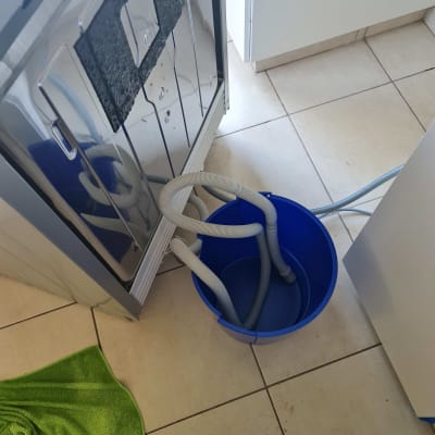 מכונת כביסה עם צינורות ניקוז לתוך דלי כחול