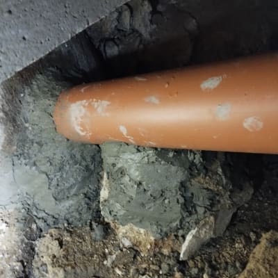 צינור כתום מחובר לקיר בטון עם טיח