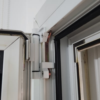 צירים לבנים של תריסים על מסגרת חלון לבנה