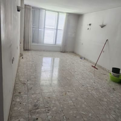 חדר ריק עם רצפת שיש וכלי ניקוי בפינה