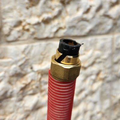 צינור אדום עם חיבור מתכת על רקע קיר