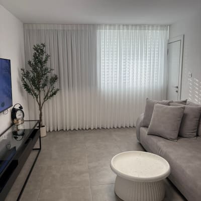 וילון לבן שקוף תלוי על חלון גדול בחדר מודרני