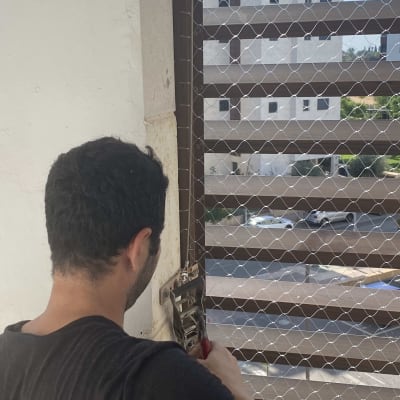 אדם מתקין רשת למניעת כניסת יונים לחלון