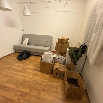 חדר עם ספה, קופסאות קרטון וציוד ארוז