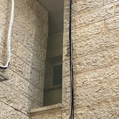 רשת יונים מותקנת על חלון בניין אבן