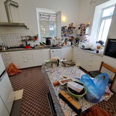 מטבח מבולגן עם כלים על השולחן ומדפים מלאים