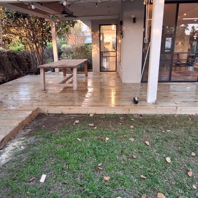 דק עץ עם כיסא ושולחן בגינה