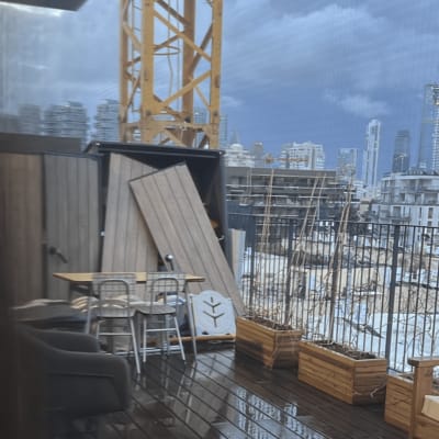 מרפסת עם ריהוט חוץ ועבודות בנייה ברקע