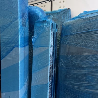 רהיטים עטופים בניילון כחול בתוך משאית הובלה