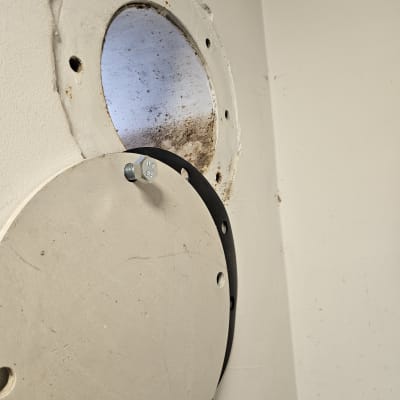 פתח עגול בקיר עם מכסה מתכת וברגים