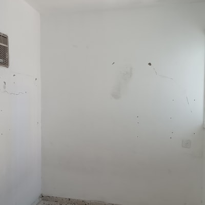 קיר עם סימני תיקון וצביעה ליד חלון ומזגן