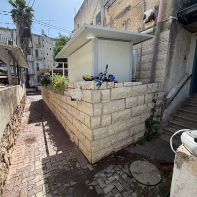 חצר עם מבנה קטן ואופניים על קיר אבן