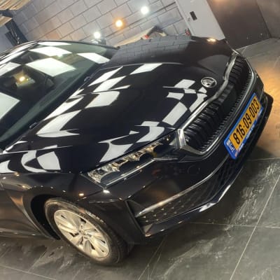 רכב שחור מבריק בחדר עבודה עם תאורה חזקה