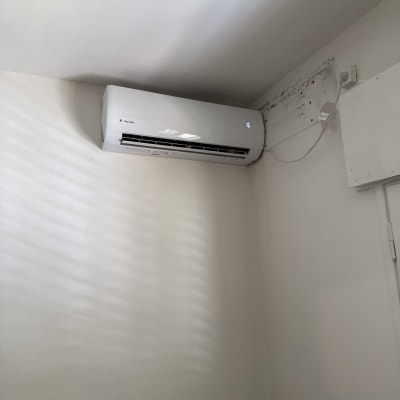 מזגן מותקן על קיר לבן עם חוט חשמל