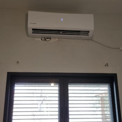 מזגן מותקן על קיר מעל חלון עם תריסים