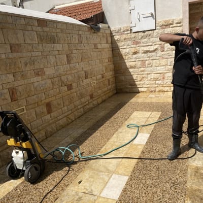 אדם משתמש במכונת שטיפה בלחץ לניקוי רצפה