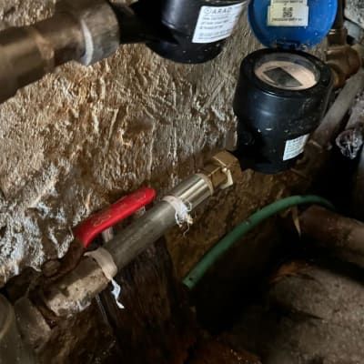 מד מים וצינורות עם ברז אדום על קיר