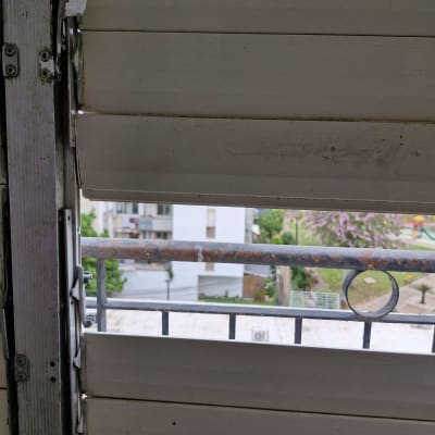 תריסים לבנים עם חלודה על מסגרת מתכת